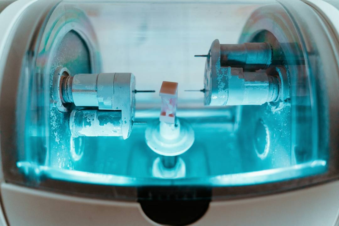 L’interno di un fresatore: le frese e il blocchetto in lavorazione, sotto la luce blu